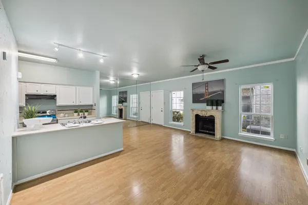 a view of a kitchen with furniture a ceiling fan and wooden floor