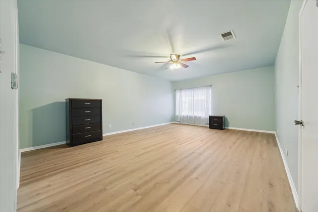 a view of an empty room with a window and dresser