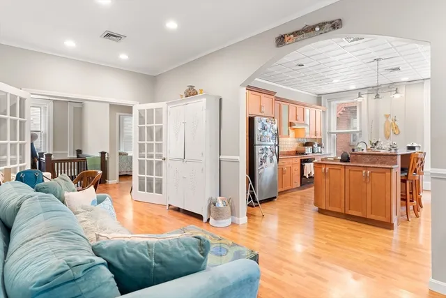 a living room with stainless steel appliances furniture windows and a kitchen view