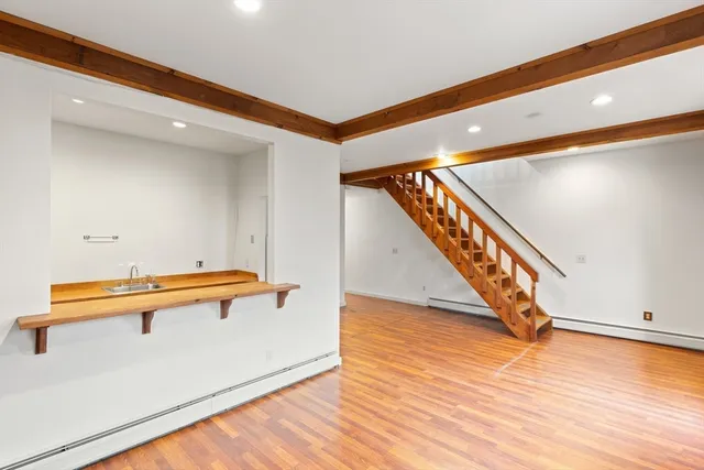 a view of an empty room with wooden floor and stairs