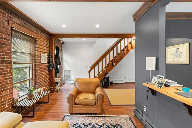 a view of a livingroom with wooden floor and stairs