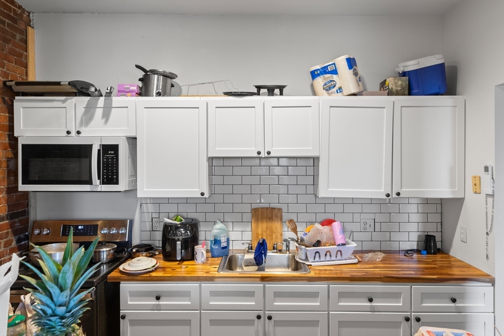 100-102 Main Street Gloucester, MA 01930 - Photo 33 of 40 a kitchen with white cabinets and appliances