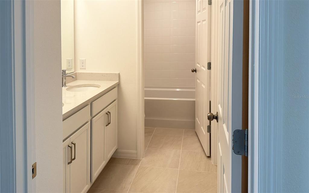 6867 Spanish Imperial Street Howey-in-the-Hills, FL 34737 - Photo 13 of 20 a bathroom with a granite countertop sink a mirror and a bathtub
