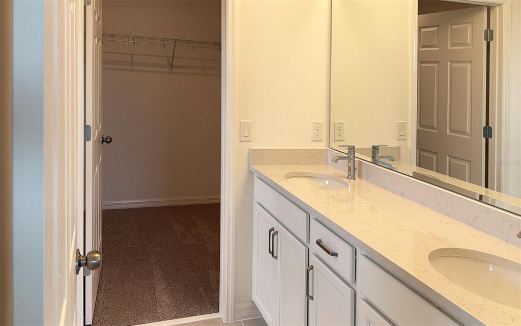 6867 Spanish Imperial Street Howey-in-the-Hills, FL 34737 - Photo 14 of 20 a bathroom with a granite countertop sink and a large mirror