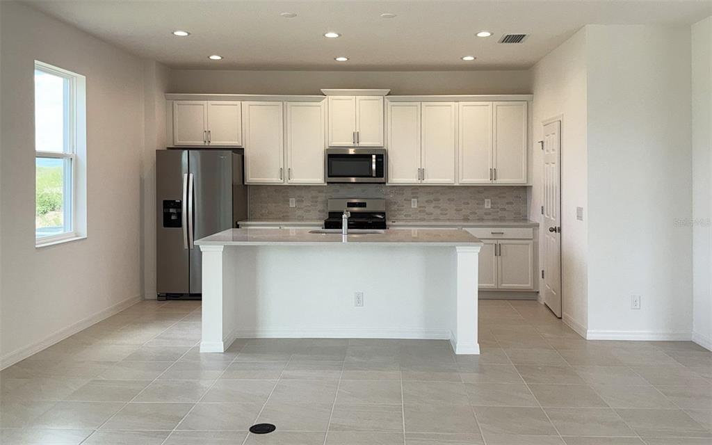 6867 Spanish Imperial Street Howey-in-the-Hills, FL 34737 - Photo 3 of 20 a kitchen with stainless steel appliances granite countertop a stove a sink and a refrigerator