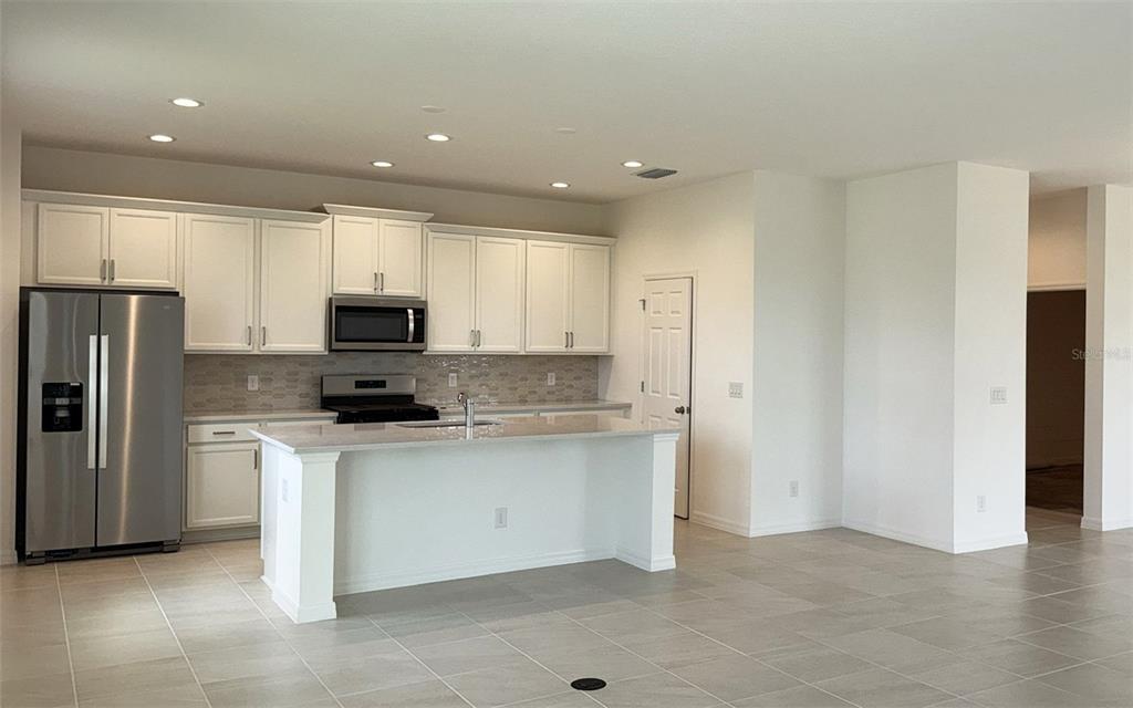 6867 Spanish Imperial Street Howey-in-the-Hills, FL 34737 - Photo 4 of 20 a kitchen with stainless steel appliances a refrigerator sink and microwave