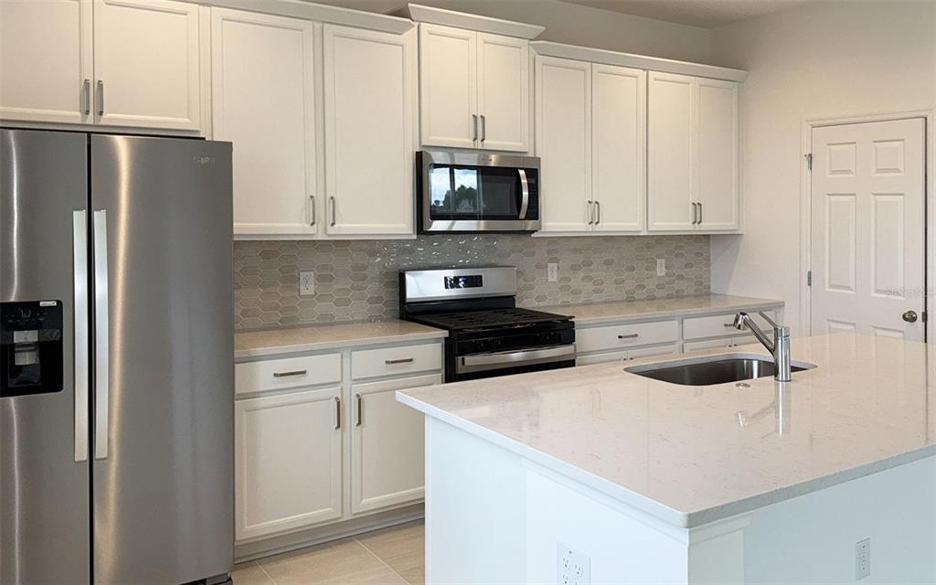 6867 Spanish Imperial Street Howey-in-the-Hills, FL 34737 - Photo 5 of 20 a kitchen with a refrigerator sink and cabinets