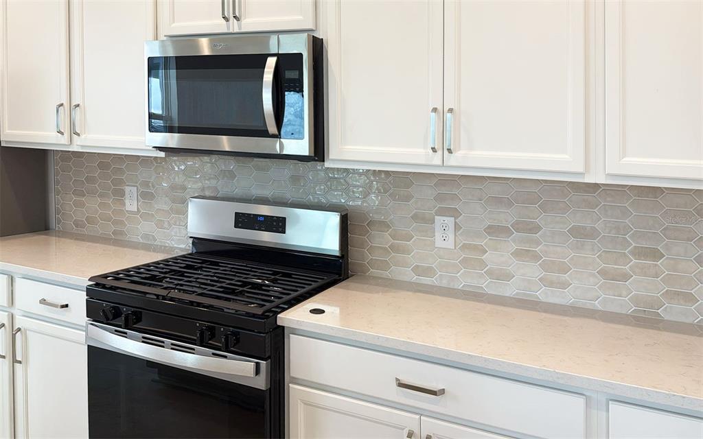 6867 Spanish Imperial Street Howey-in-the-Hills, FL 34737 - Photo 6 of 20 a kitchen with granite countertop cabinets stove top oven and microwave
