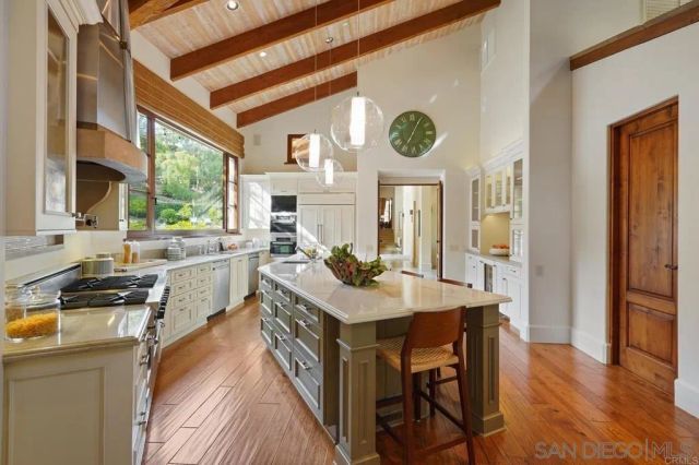 a open kitchen with stainless steel appliances granite countertop a stove a refrigerator a dining table and chairs with wooden floor