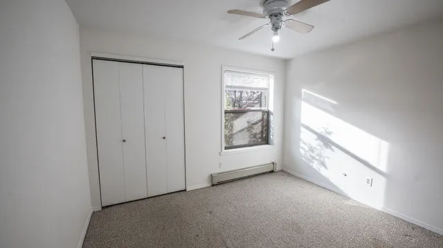 an empty room with chandelier fan and windows
