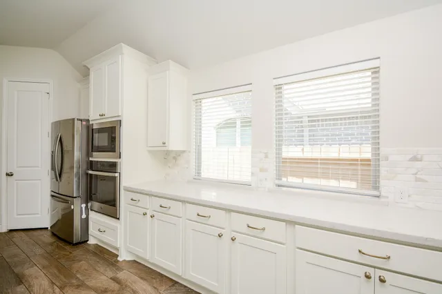a view of an empty room with wooden floor fireplace and a window
