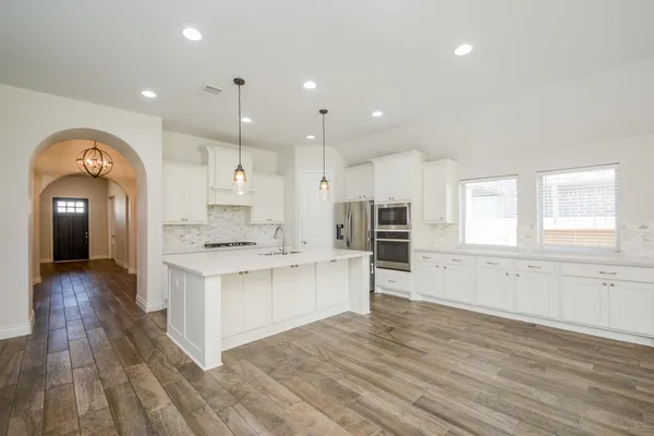 a large kitchen with stainless steel appliances granite countertop a lot of counter space and wooden floors