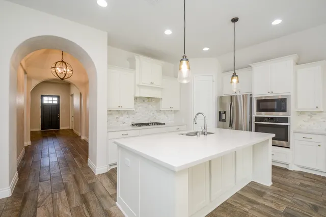 a large kitchen with stainless steel appliances a large center island attached withe living room