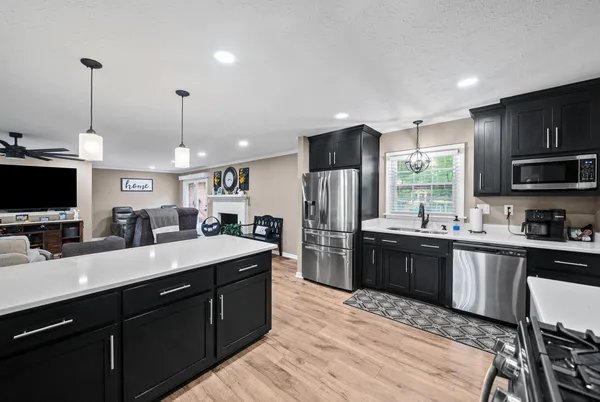 a large kitchen with stainless steel appliances kitchen island granite countertop a sink counter space and a view of living room