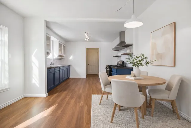 a view of kitchen and empty room with wooden floor