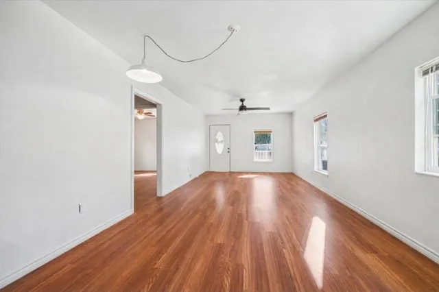 a view of empty room with wooden floor and fan