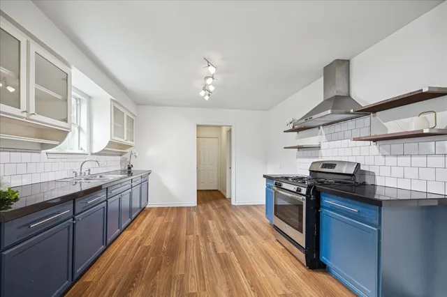 a large kitchen with granite countertop a large counter top space a sink stainless steel appliances and cabinets