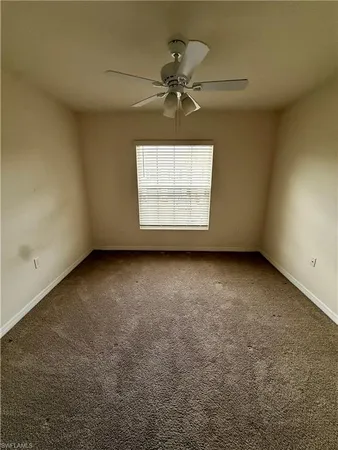 an empty room with a ceiling fan and a window