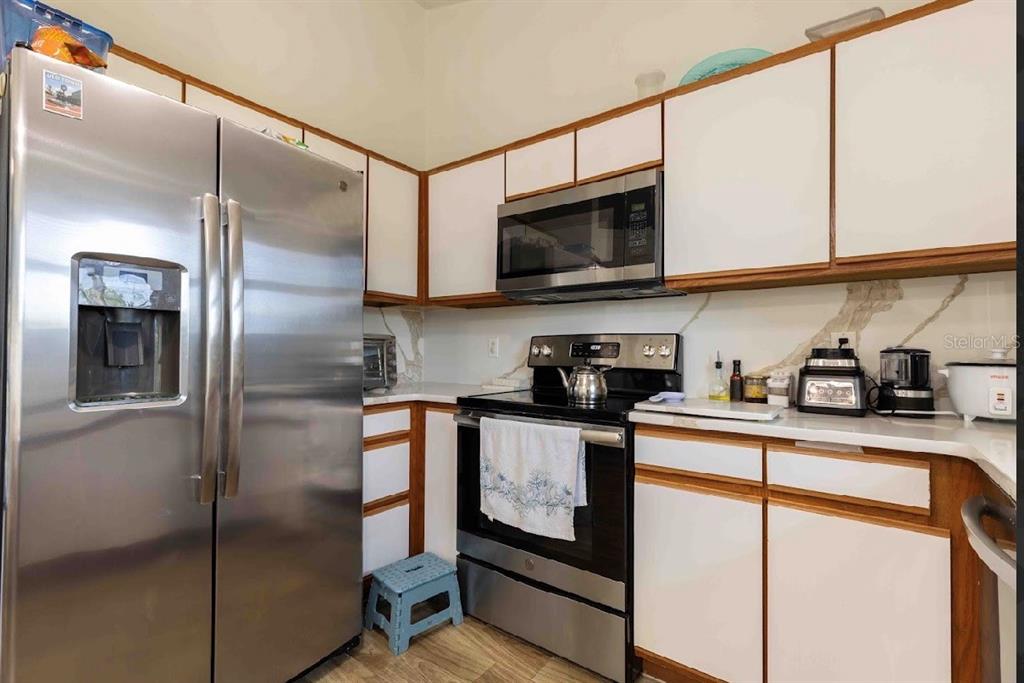 10665 Huntridge Road Orlando, FL 32825 - Photo 10 of 12 a kitchen with stainless steel appliances granite countertop a refrigerator a stove and a sink with wooden floor