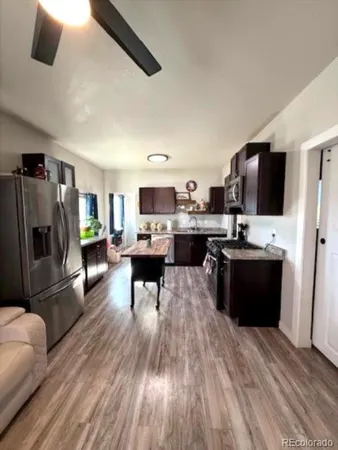 a living room with stainless steel appliances furniture and a flat screen tv