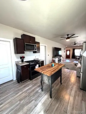 a living room with stainless steel appliances kitchen island furniture and a flat screen tv