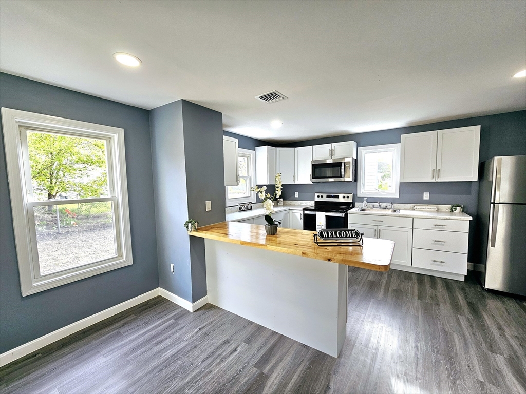 9 Wellington Street Webster, MA 01570 - Photo 10 of 37 a kitchen with stainless steel appliances granite countertop a refrigerator a stove top oven a sink dishwasher and white cabinets with wooden floor