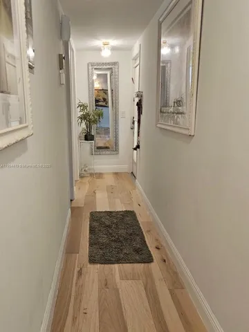 view of a hallway with wooden floor and a mirror
