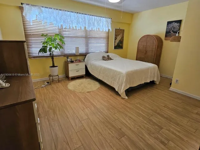 a bedroom with a bed chair and wooden floor