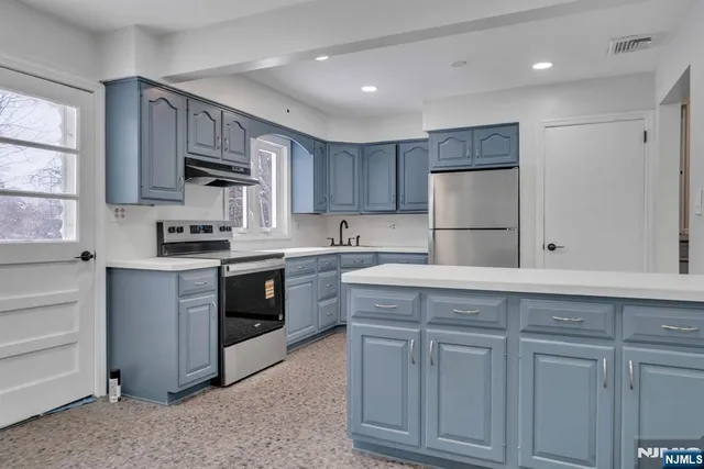 a kitchen with kitchen island granite countertop white cabinets and stainless steel appliances