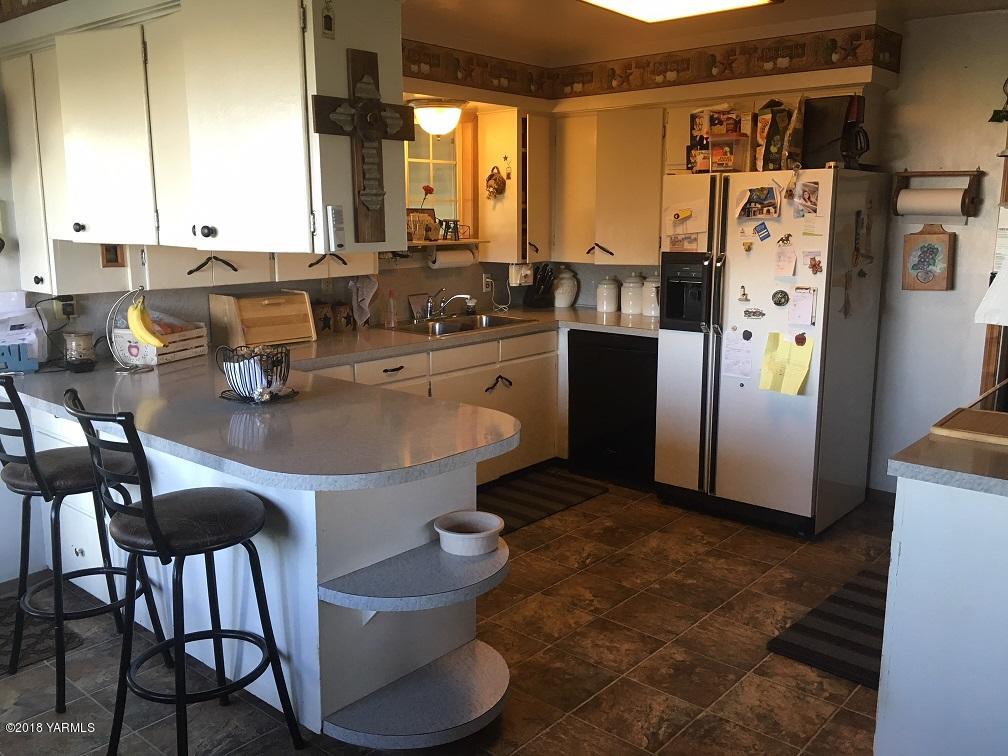 590 Hudson Road Granger, WA 98932 - Photo 24 of 26 a kitchen with stainless steel appliances granite countertop a refrigerator a stove and white cabinets with island chairs