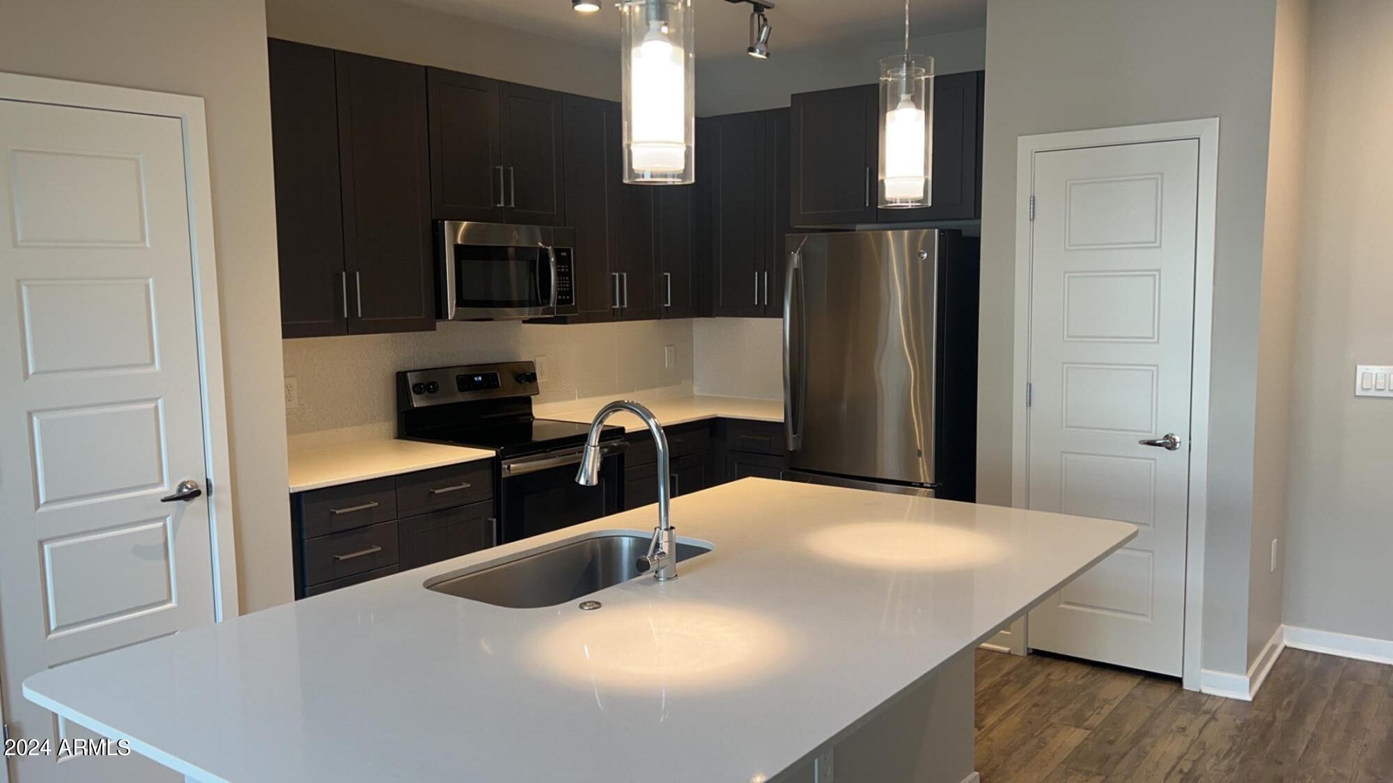 4949 North 7th Street, Unit A3 Phoenix, AZ 85014 - Photo 3 of 22 a kitchen with stainless steel appliances kitchen island granite countertop a refrigerator a sink a stove and microwave