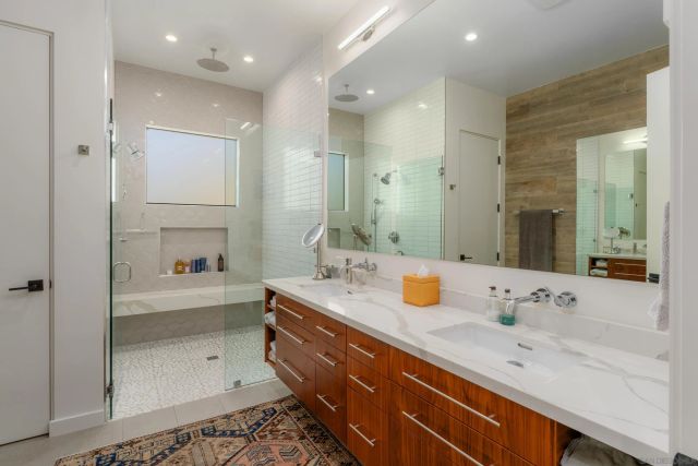 a bathroom with a sink double vanity granite tub shower and a mirror