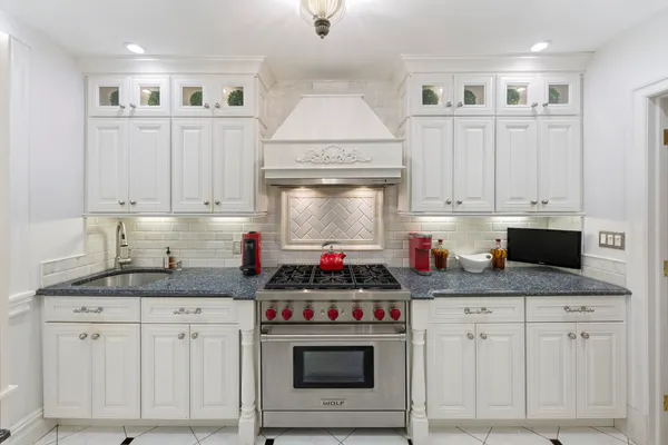 a kitchen with granite countertop a sink cabinets and stainless steel appliances