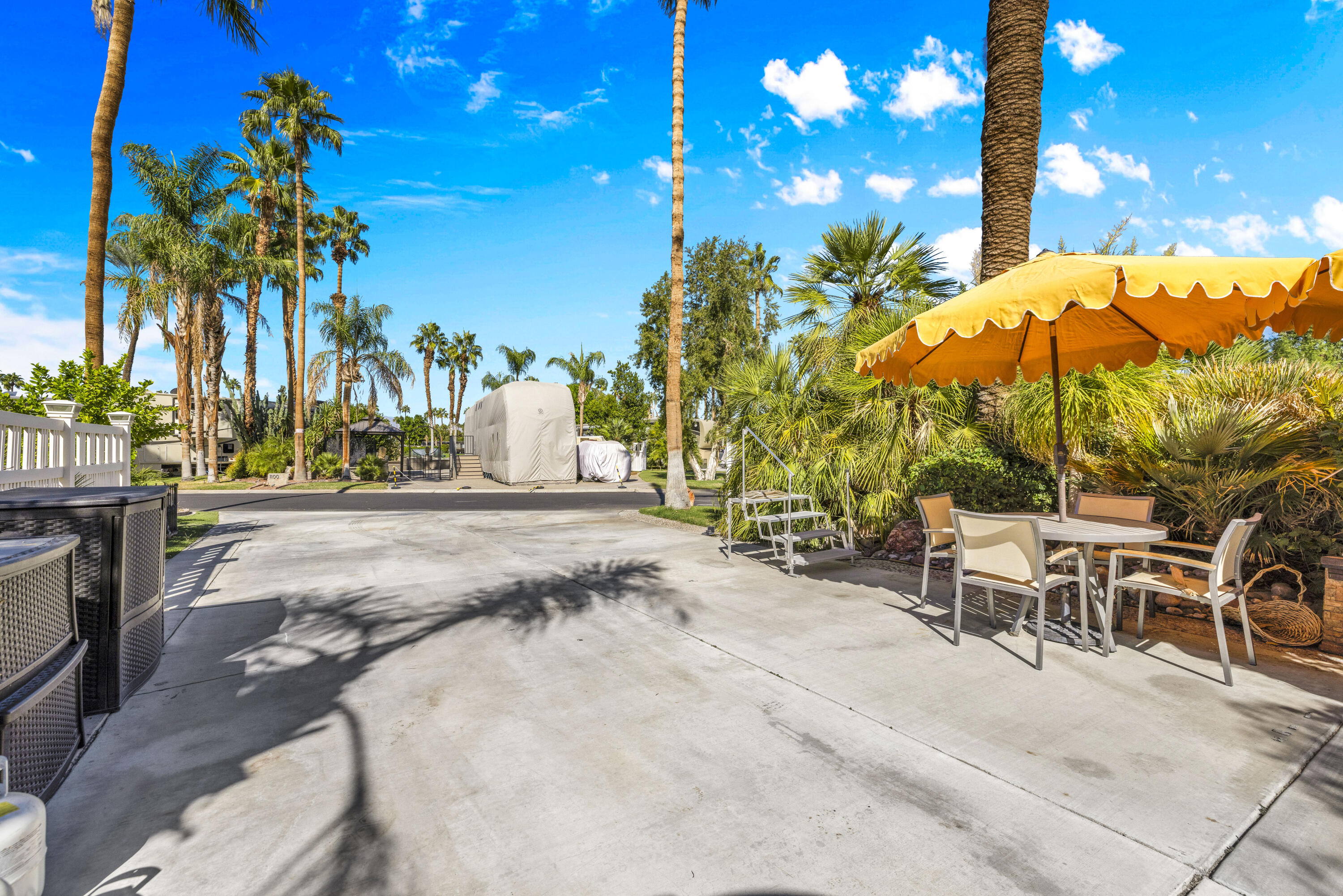69411 Ramon Road, Unit 1011 Cathedral City, CA 92234 - Photo 12 of 46 a view of a patio with a table and chairs under an umbrella with palm trees