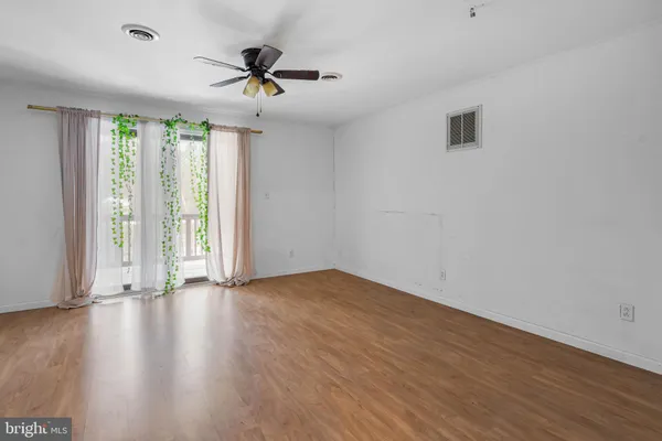 a view of a room with wooden floor and ceiling fan