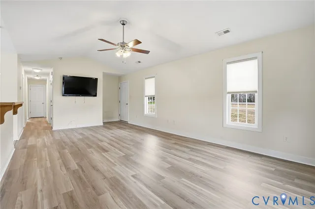 a view of an empty room with a window and wooden floor