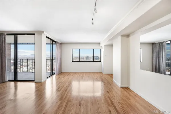 a view of an empty room with window and wooden floor