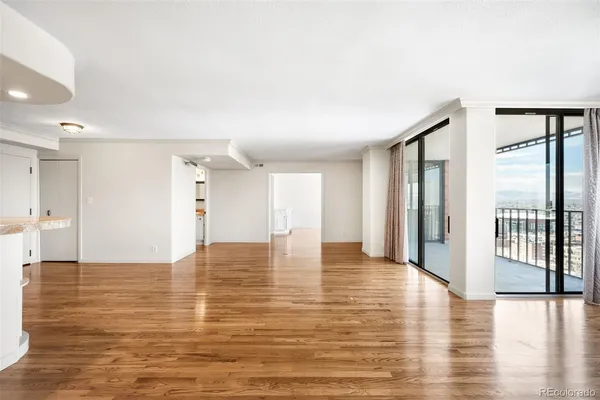 a view of an empty room with window and wooden floor
