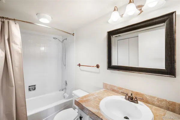 a bathroom with a sink a toilet and shower a mirror