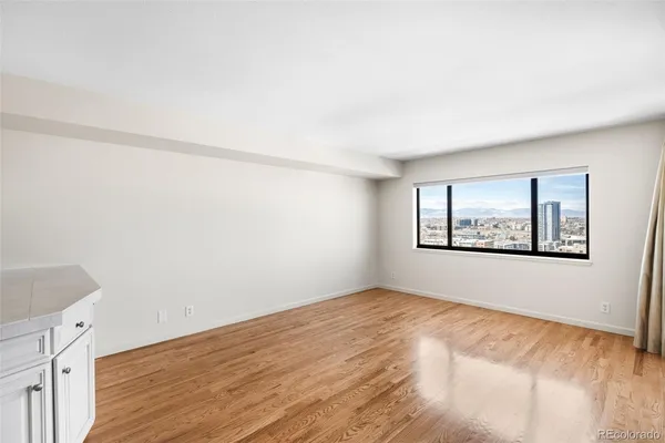 a view of an empty room with window and wooden floor