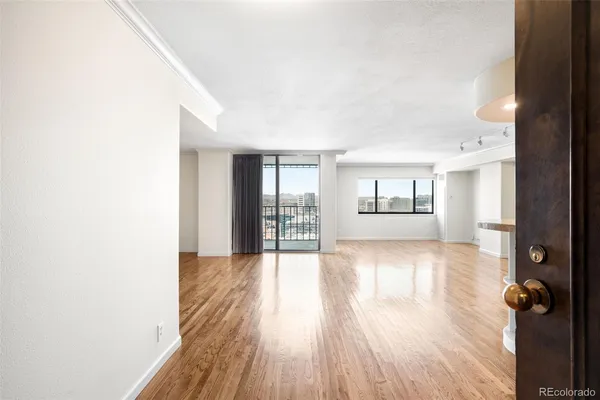 a view of an empty room with wooden floor and a window