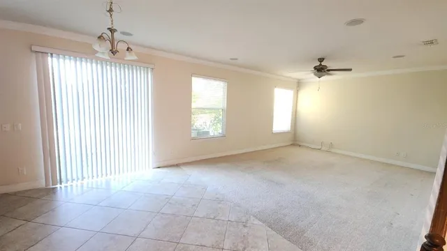 an empty room with windows and chandelier fan