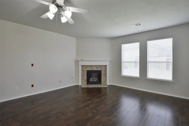 an empty room with wooden floor chandelier and windows