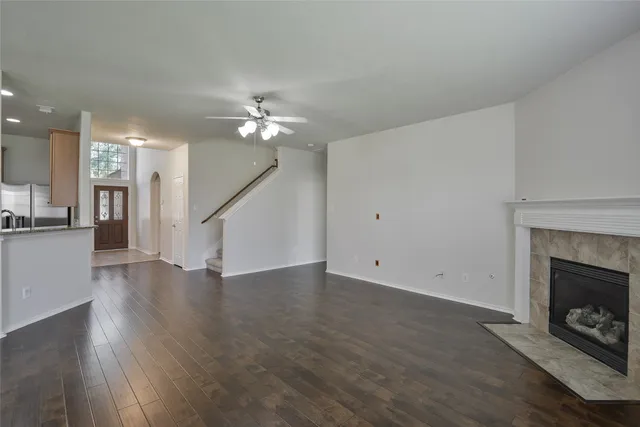 a view of an empty room with wooden floor fireplace and a window