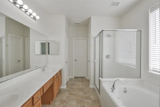 a spacious bathroom with a tub a sink and mirror