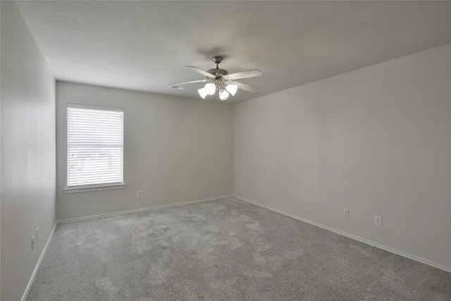 an empty room with a window and a ceiling fan