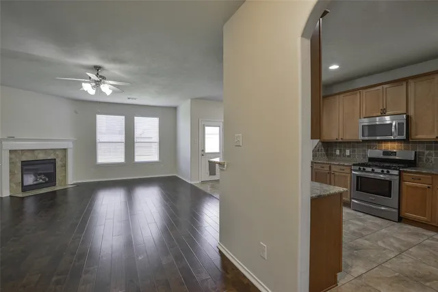 a view of a kitchen with a stove wooden cabinet a refrigerator a ceiling fan and wooden floor