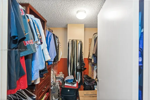 a view of walk in closet with clothes and shoes