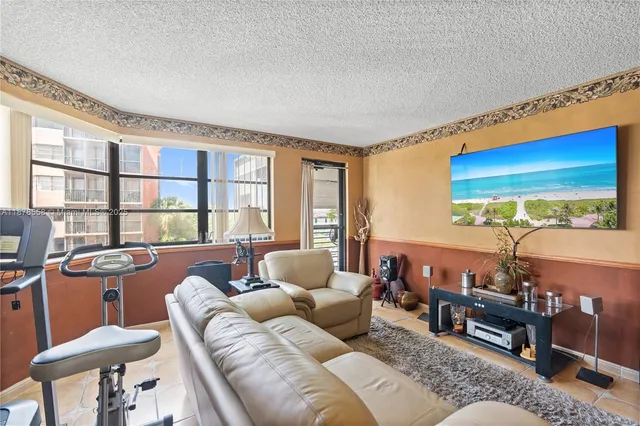 a living room with furniture a flat screen tv and a floor to ceiling window
