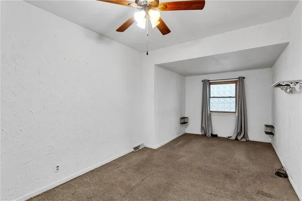 an empty room with chandelier fan and windows